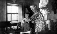Клинова Елизавета Ивановна одевает сына Володю у люльки. Деревня Клиново. 1963 г.